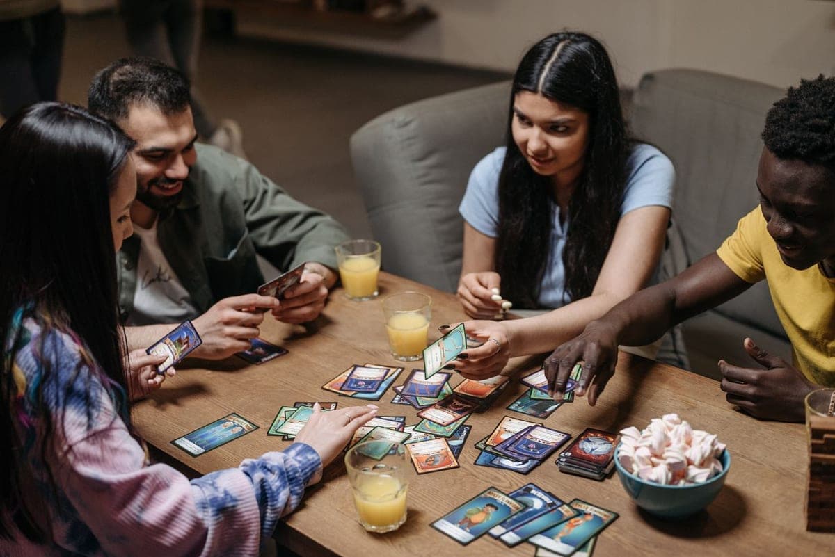 Friends around a table mid card game, watching each other closely